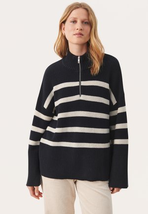 Marineblå og cremefarvet stribet sweater med høj hals og halv lynlås. Har en løs pasform og ribbet tekstur. Behageligt, afslappet design.