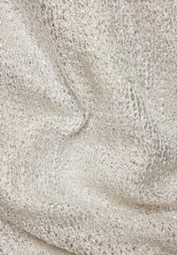 Strukturiertem Stoff in einer hellen Cremefarbe mit metallischen silbernen Akzenten, der eine zerknitterte Oberfläche mit einem gewebten Muster zeigt.