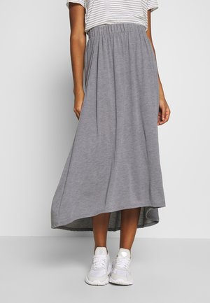 Grijze maxi-rok gemaakt van zachte stof, met een elastische tailleband, A-lijn ontwerp en een langere zoom aan de achterkant. Gecombineerd met witte sneakers.