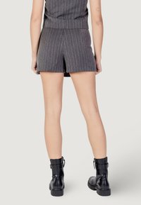 Shorts grigi a righe sottili con vita alta e dettaglio di spacco frontale, abbinati a stivaletti neri con suola texturizzata.