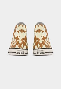 Καφέ και κρεμ αθλητικά παπούτσια Converse All Star με σχέδιο ζώου, τύπου high-top, εμφανιζόμενα από την πίσω πλευρά σε λευκό φόντο.
