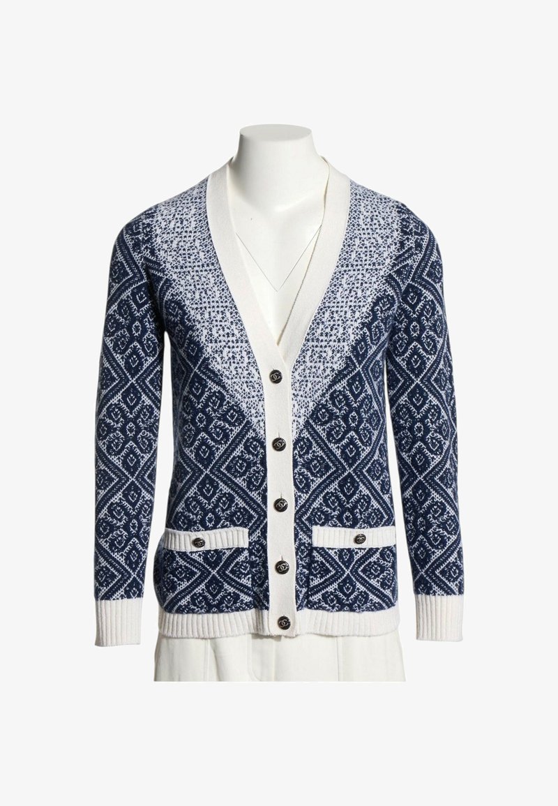Cardigan tricoté bleu marine et blanc avec des motifs géométriques, boutons sur le devant, deux poches avant et poignets et ourlet côtelés blancs.