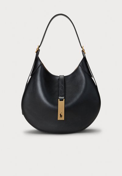Zwarte leren hobo tas met een gebogen vorm, voorzien van een gouden hardware-accent en een opvallend logo aan de voorkant, met een gladde textuur en een schouderriem.