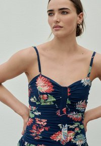 Blumenmuster-Kleid mit navy Hintergrund, figurbetontem Schnitt, geraffter Textur, verstellbaren Spagetti-Trägern und Knopfdetails vorne.