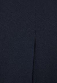 Mörkblå knälång kjol i ribbat material, med en slits framtill för extra designinslag. Jämn textur genom hela kjolen.