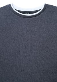 Maglione grigio scuro realizzato in tessuto testurizzato, con collo a girocollo e un bordo bianco in contrasto, e un'etichetta con il nome del marchio "CALLIOT."