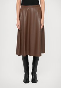 Brown faux leather midi skirt with a flared design; smooth texture and wide waistband; paired with knee-high black boots.