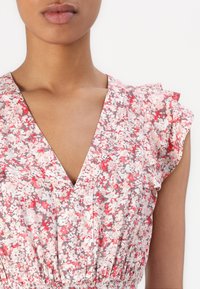 Φλοράλ φόρεμα με V-λαιμόκοψη, διακοσμημένο με ροζ και κόκκινα μοτίβα σε ανοιχτό φόντο. Ραμμένα μανίκια και λεπτομέρεια με ελαστική μέση.