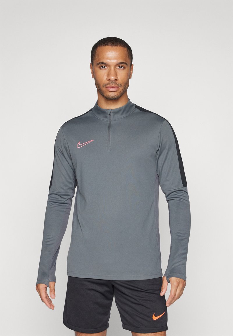 Sivi dugih rukava sportski gornji dio s četvrtim patentnim zatvaračem, s crnim detaljima na ramenima i ružičastim Nike logotipom na lijevoj strani prsnog koša.
