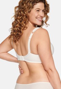 White ribbed bra with adjustable straps and a hook-and-eye closure. Features a round design and smooth texture. Minimalist style.