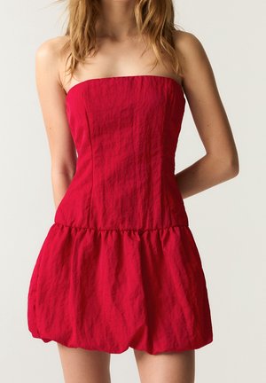 Czerwona sukienka bez ramiączek z dopasowanym górnym stanem i bufiastym, marszczonym dołem. Wykonana z teksturowanej tkaniny, z gładką górą i marszczoną talią.