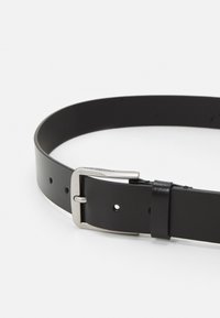 Cintura in pelle nera con fibbia in metallo argentato, chiusura a un'unica staffa e molteplici fori di regolazione lungo la cinghia per la misura.