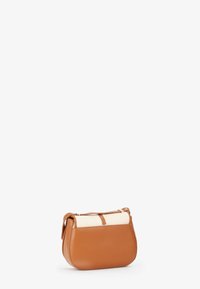 Bolso de mano de cuero marrón con una parte superior de tela color crema. Forma redondeada, correa ajustable, cuenta con un cierre de cremallera y detalles de costura sutiles.