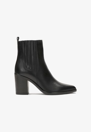 Crne kožne gležnjače s naoštrenim vrhom i srednjim blok petom. Imaju vertikalne nabore i uvučenu petlju straga. Glatka tekstura.