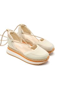 Chaussures à plateforme en toile couleur beige clair avec des accents oranges. Elles présentent une partie avant arrondie, des côtés ouverts et un tissu texturé. Lacets tressés pour le maintien.