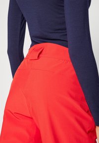 Rode broek met een gladde textuur en een zijzak, gecombineerd met een aansluitend marineblauw longsleeve top met een gecontourde taille.