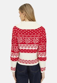Maglione a maglia rosso e bianco con un ampio colletto, modelli intricati e maniche lunghe. Texturizzato con bande a contrasto e motivi decorativi.