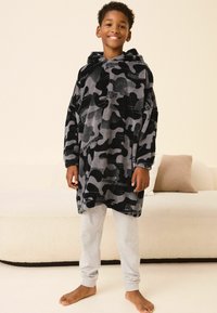 Hættejakke i sort og grå camouflage mønster, lavet af blødt materiale, båret over grå sweatpants, fremvist på en neutral baggrund.