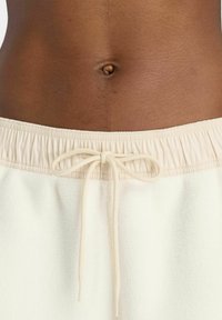 Romige fleece shorts met een elastische tailleband en een trekkoord. De stof heeft een zachte textuur en is vrij van patronen of metalen details.