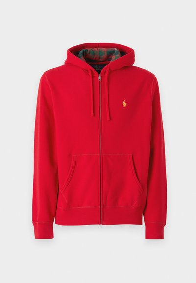 Sudadera roja con cremallera fabricada en tejido suave. Cuenta con un bolsillo frontal, capucha ajustable y un logotipo sutil. Interior forrado con un patrón de cuadros.