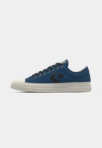 Blue canvas sneakers with a white rubber toe cap; features black star and chevron logo, flat laces, and a textured sole.