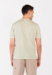 Camiseta de rayas beige claro con mangas cortas, que muestra una textura suave. El diseño presenta líneas horizontales sutiles y un cuello redondo.