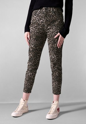 Pantaloni con stampa leopardata nelle tonalità di marrone e nero, fit affusolato, dotati di tasche anteriori e vita alta, abbinati a sneakers beige alte.