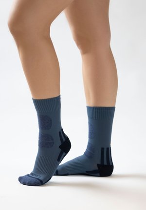 Blauwe enkelsokken met ribbelkanten, voorzien van donkerblauwe cirkelpatronen en zwarte accenten. Gemaakt van ademend, rekbaar materiaal.