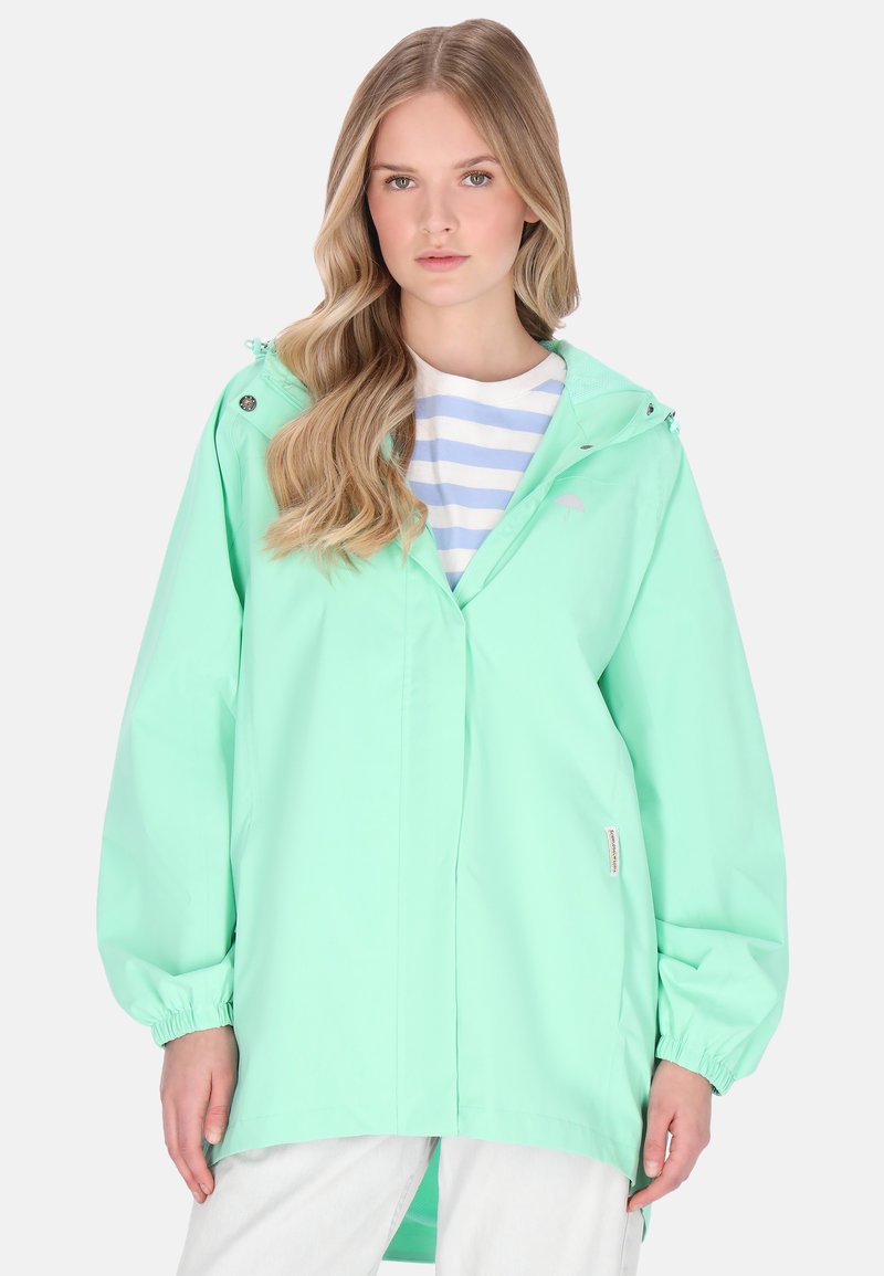Mentazöld, kapucnis vízálló dzseki, rugalmas mandzsettákkal, elöl gombos záródással és bő szabással; fehér-kék csíkos ing felett rétegezve.