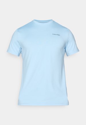 T-shirt en coton bleu clair à manches courtes, col rond, avec un petit logo noir "Calvin Klein" sur le haut à gauche de la poitrine. Texture lisse.