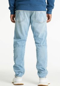 Svetlo modri jeans z ohlapnim krojem, ki imajo dva zadnja žepa in diskretne šive. Nosi se z belimi supergami.