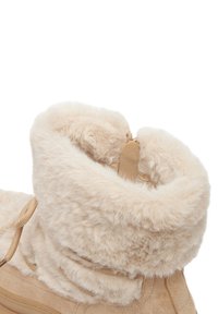 Bocanci bej cu guler pufos, asemănător blănii și corp moale din suede. Sforile sunt vizibile în față, alături de o suprafață netedă, texturată.