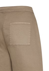 Vue arrière d'un pantalon beige montrant une poche carrée à l'arrière avec des coutures visibles sur un tissu uni.