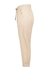 Pantalons de jogging beiges avec une taille élastique et un cordon de serrage réglable, dotés de poches latérales et de chevilles côtelées. Texture de tissu lisse.