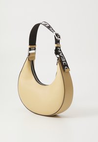 Yellow leather hobo bag with a curved shape, black and white adjustable strap featuring text, and a silver zipper. Textured surface.
