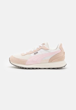 Scarpe sportive con una combinazione di rete bianca e suede beige. Accenti rosa sui lati e sulla linguetta, con una suola grigia testurizzata.