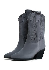 Cizme de cowboy din suede gri, cu vârf ascuțit, un design floral perforat și toc îngrămădit. Cizmele au cununi pentru a fi purtate cu ușurință.