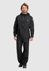 Zwarte waterdichte jas met capuchon en rits, gecombineerd met bijpassende zwarte broek. Reflecterende accenten op de mouwen en zijnaad. Lichtgewicht materiaal.