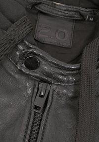 Schwarze Lederjacke mit strukturiertem Finish, ausgestattet mit einem Reißverschluss vorne, schwarzem Metall und einem Etikett mit "2.0" und Größe "M" innen.