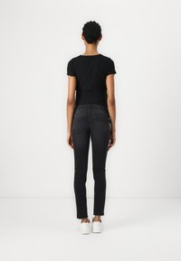 Svart, ribbestrikket topp med kort erme kombinert med svarte skinny jeans med en falmet vask og rå kant. Fottøy: hvite joggesko.