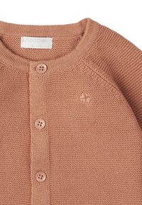 Ljusrosa stickad kofta med rund hals, tre knappar och en liten blommig broderi på vänster sida. Mjuk textur, avslappnad design.