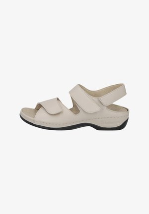 Beige sandals with adjustable Velcro straps, open toe design, cushioned insole, and black outsole. Textured leather upper.