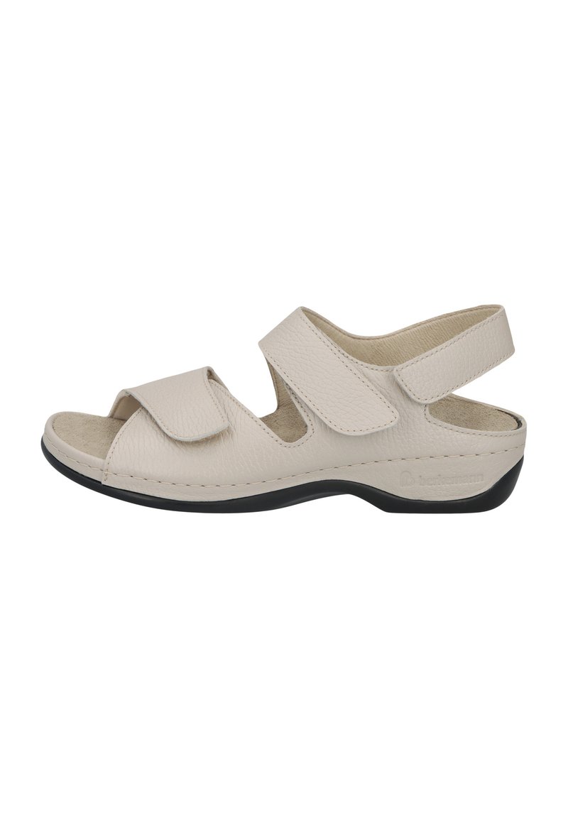 Beige sandals with adjustable Velcro straps, open toe design, cushioned insole, and black outsole. Textured leather upper.
