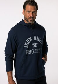 Sudadera con capucha de color azul marino que presenta un bolsillo frontal y un diseño gráfico que dice "PROYECTO YUNQUE DE HIERRO" en una fuente gris desgastada.