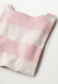 Pull doux plié avec de larges rayures horizontales roses et blanches et un col rond sur une surface blanche.