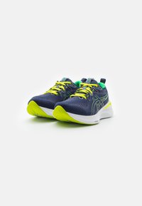 Scarpe da corsa con una tomaia in rete blu navy, accenti verde neon, lacci gialli luminosi e una suola intermedia bianca con grip testurizzato.