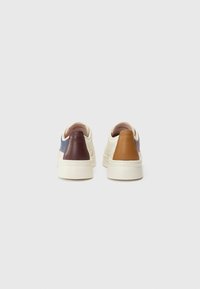 Lave sneakers i creme med en marineblå overdel og mørkerøde samt brune hælaccenter. Glat lædertekstur med et minimalistisk design.