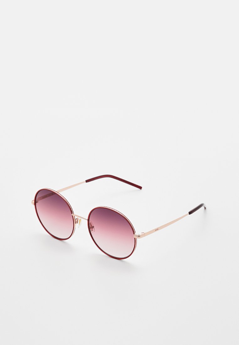 Round sunglasses with a gradient burgundy lens, gold metal frame, and burgundy-accented temples. Overall smooth texture and lightweight design.