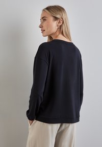 Marineblauer Pullover mit lockerer Passform, gerippten Bündchen und Saum. Weicher Stoff mit rundem Ausschnitt und leichter Textur.