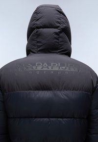 Personne portant une doudoune noire avec capuche relevée, montrant le détail du dos et le logo réfléchissant "Napapijri" sur les épaules.